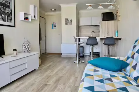 alt="Résidence – Séjour avec canapé-lit, commode et télévision"