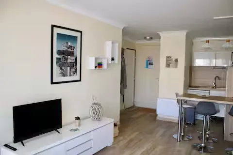 alt="Résidence – Séjour avec canapé-lit, commode et télévision"