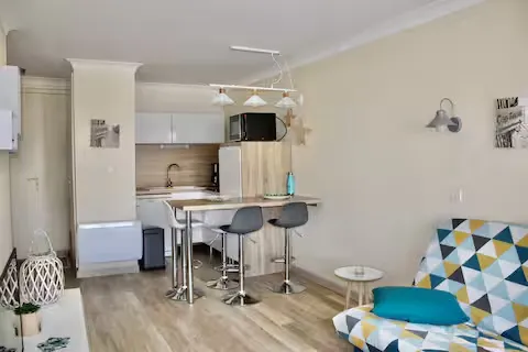 alt="Résidence – Séjour avec canapé-lit, commode et télévision"