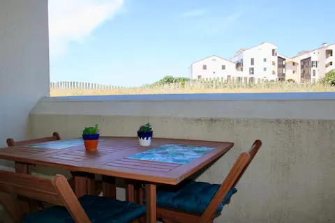 alt="Résidence – Terrasse avec table et chaises côté jardin et piscine"