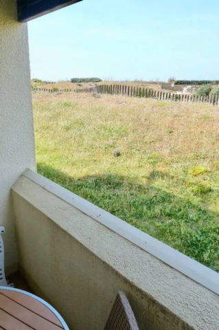 alt="Résidence – Terrasse avec table et chaises côté jardin et piscine"